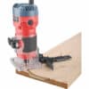 A 510W red and black milling machine cuts a groove in wood with a clear base and adjustable guide.