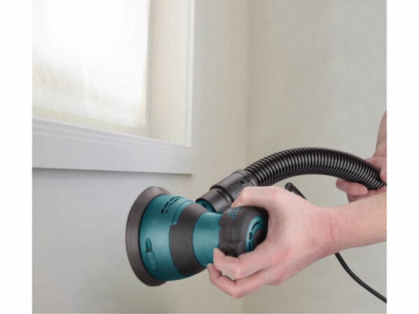 Una persona utilizza una levigatrice orbitale monomanuale da 125 mm e 350 W con attacco per tubo flessibile su una parete.