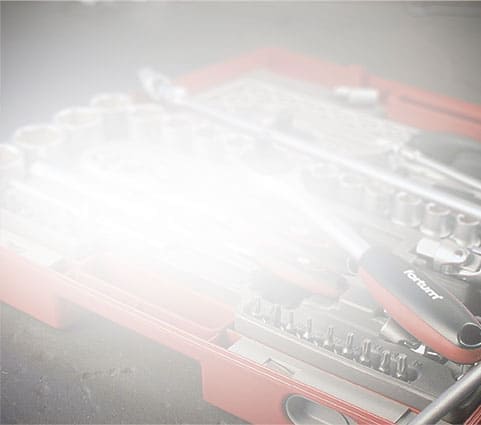 A red toolbox with sockets and screwdrivers is partly hidden by bright, hazy light.