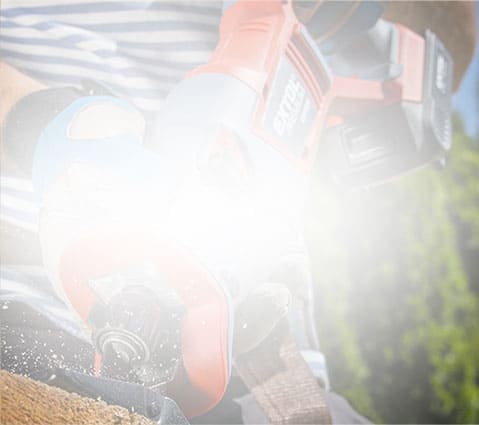 Person using a power tool on wood, with shavings and bright light partially obscuring the scene.