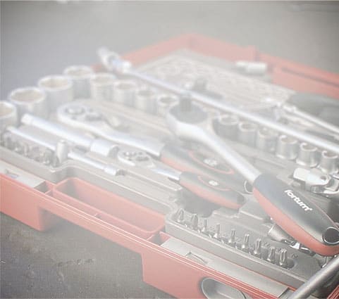 Red tool kit with socket wrenches, ratchets, and screwdriver heads under a slight foggy blur.