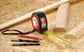 A tape measure, drill bits, and cut wood pieces are arranged on a wooden work surface.