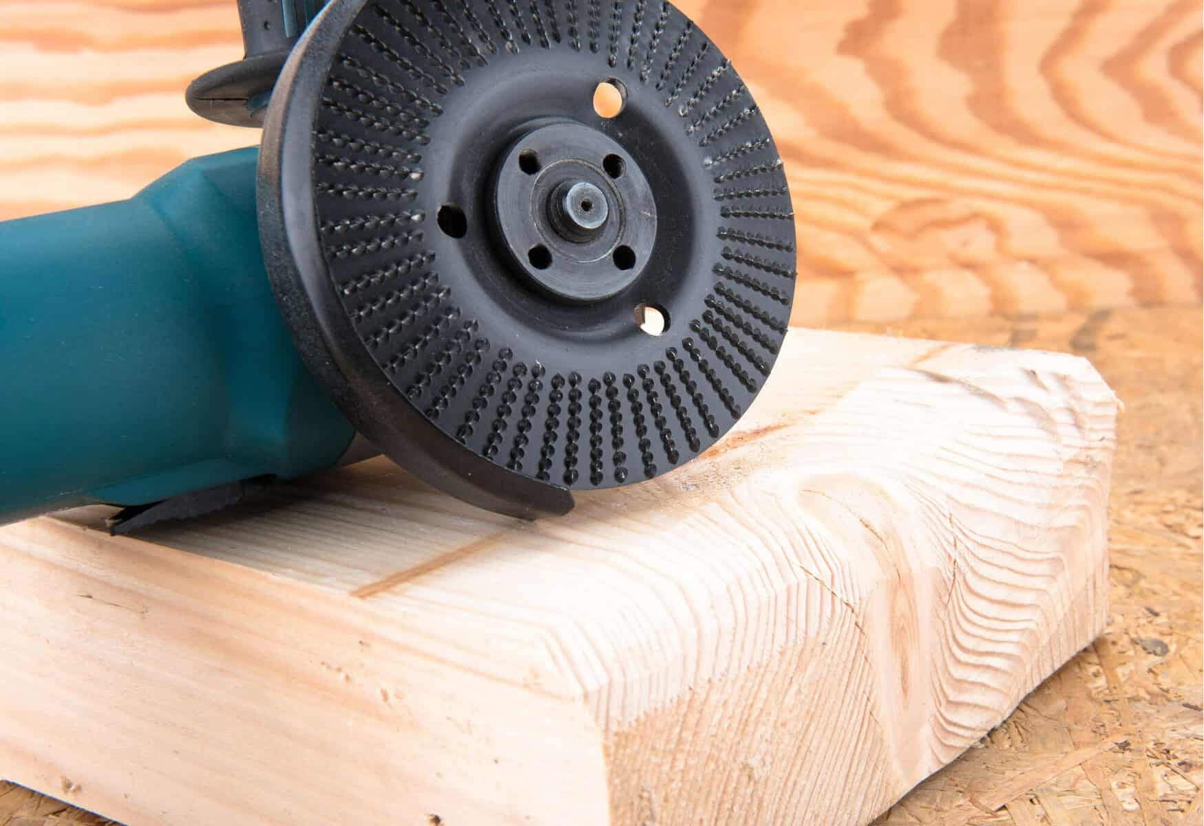 Angle grinder with a circular blade resting on grooved, unfinished wood.