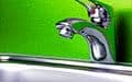A chrome bathroom faucet and sink appear against a bright green wall.