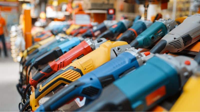 Power tools like drills and grinders lined up on a hardware store shelf.