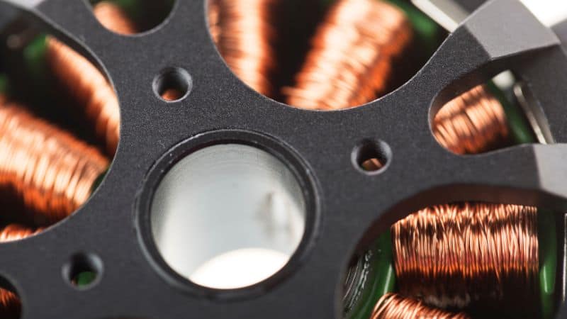 Copper wire windings inside an electric motor rotor, framed by black metal.
